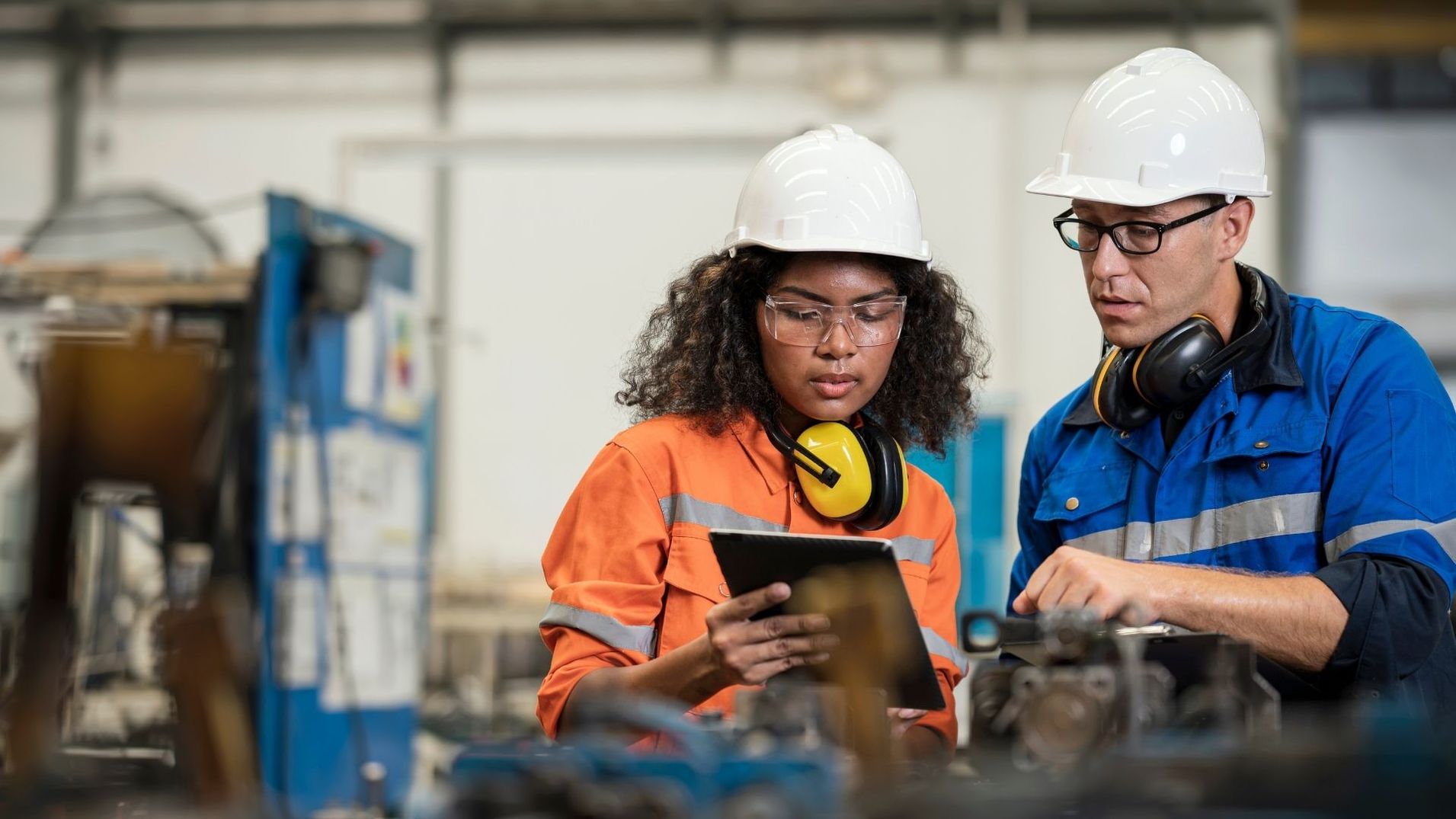 people at work in hard hats on a tablet