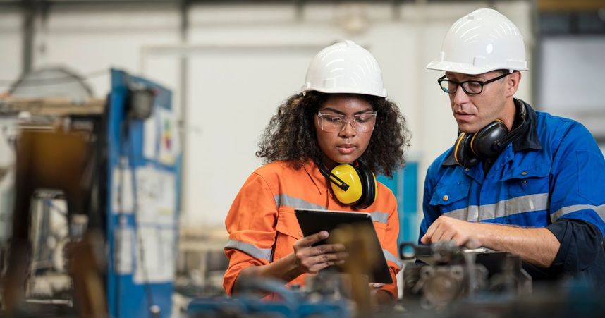 people at work in hard hats on a tablet