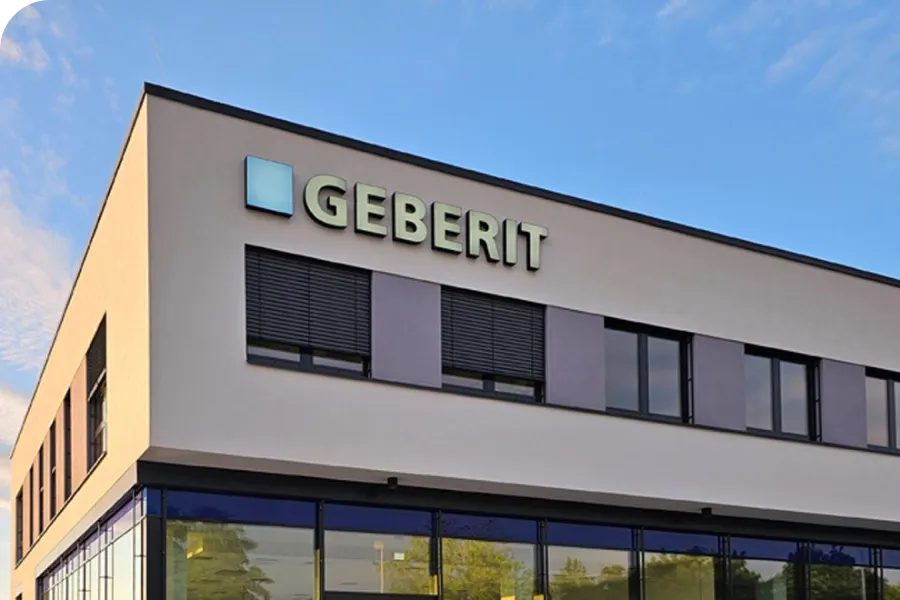 Modern building with "Geberit" sign on the facade, featuring large windows and a clear blue sky in the background.