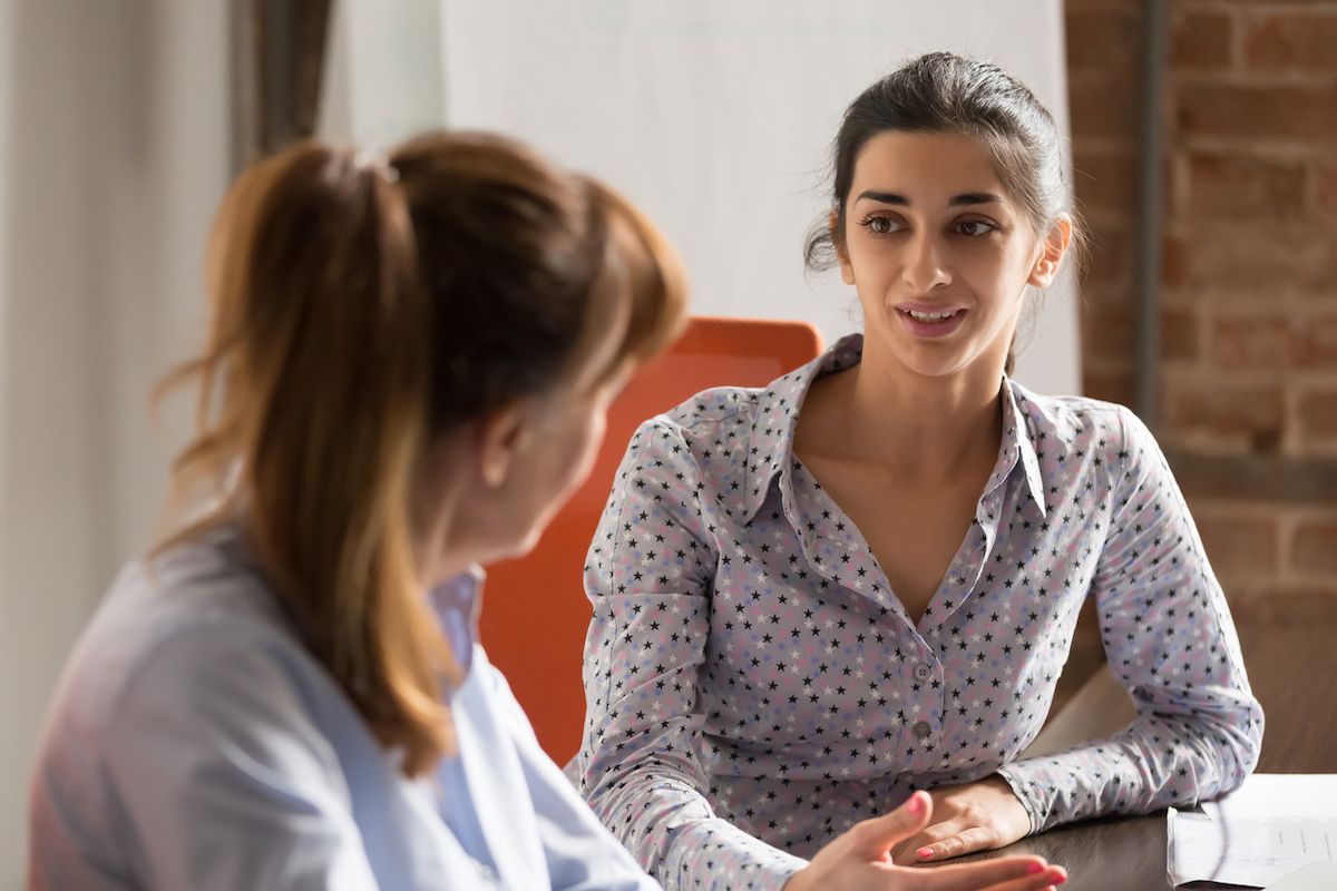 Two women sit down for a conversation in an office