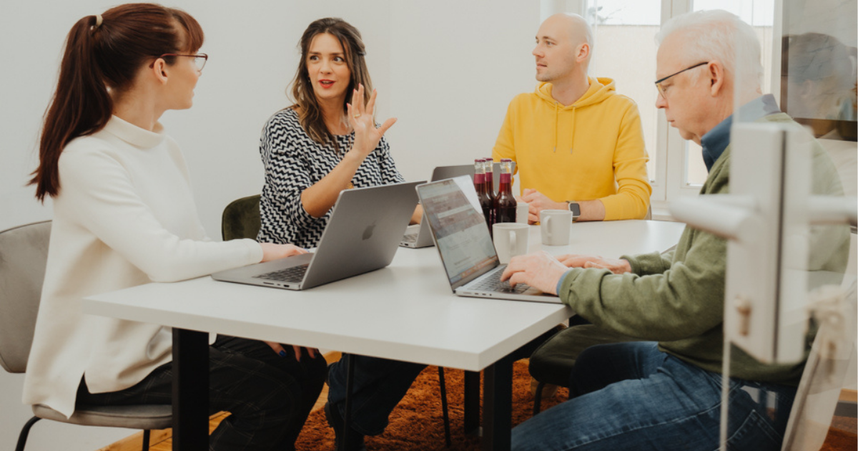 coworkers speaking around a table with open laptops