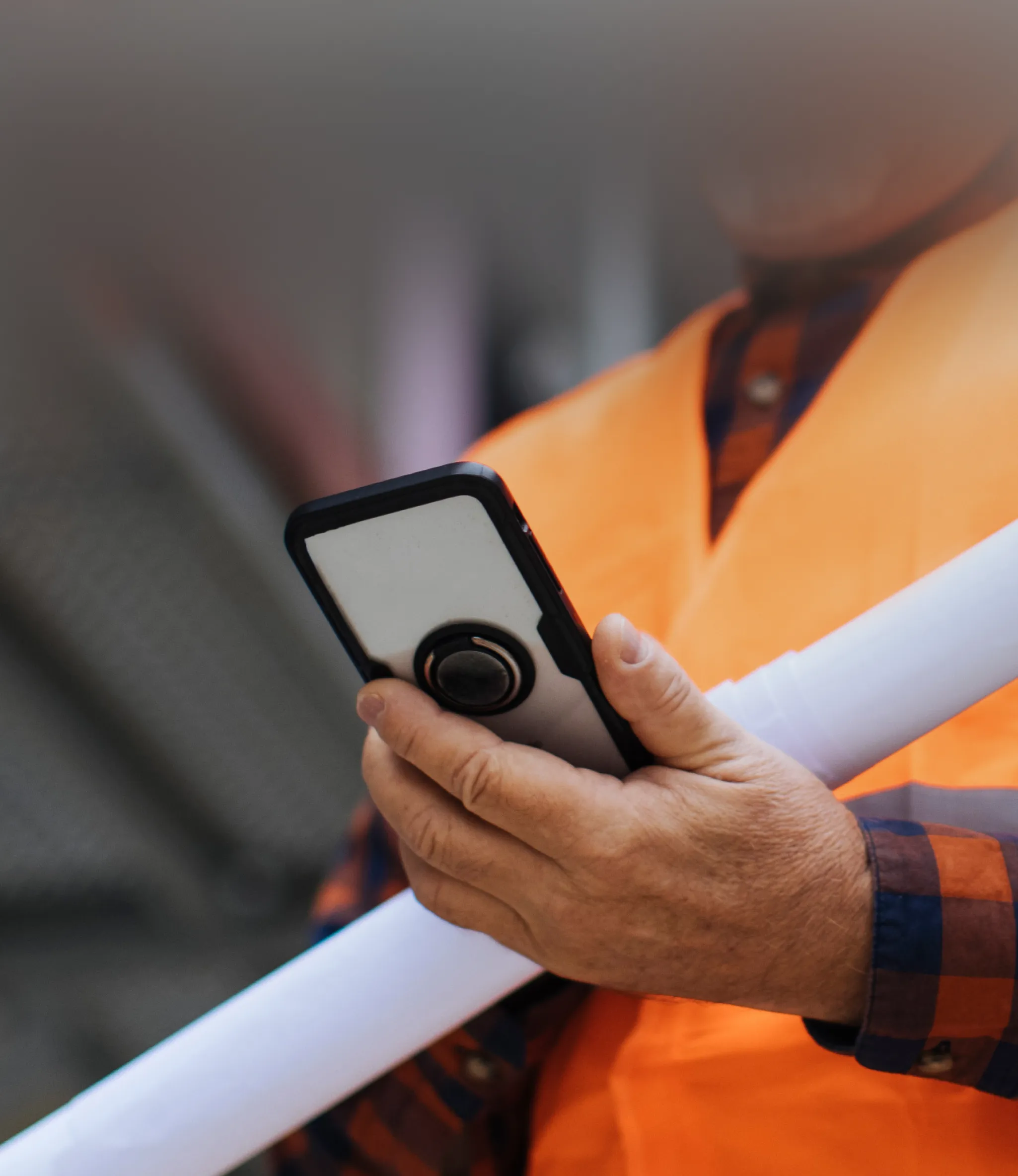 A group of construction workers in safety vests and helmets stand together, discussing at a worksite.