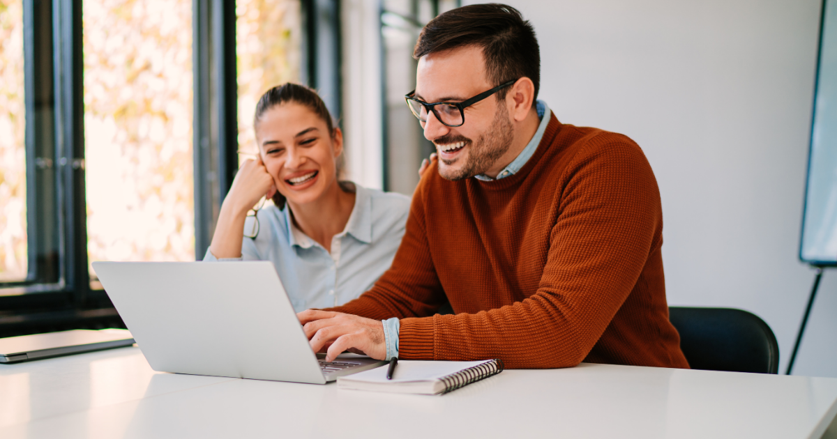 two coworkers smiling over a laptop