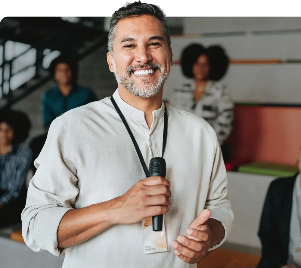 A conference speaker holding a microphone and smiling