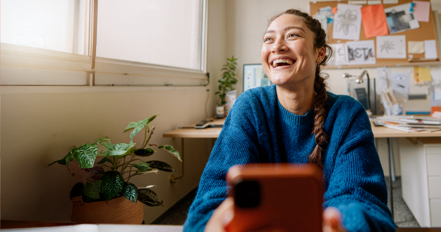 woman laughing in office while holding phone