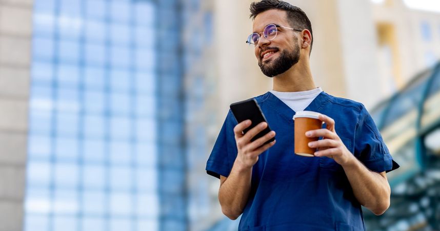 man in scrubs smiling with phone