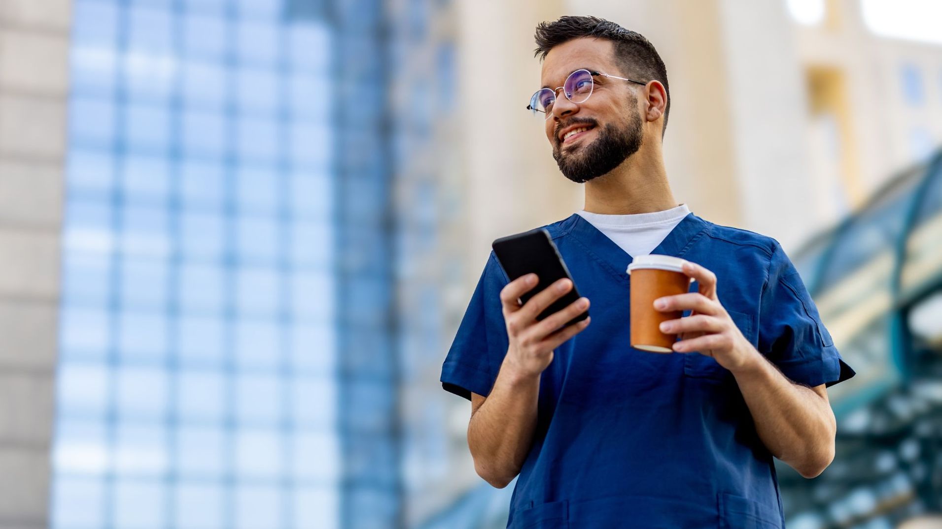man in scrubs smiling with phone