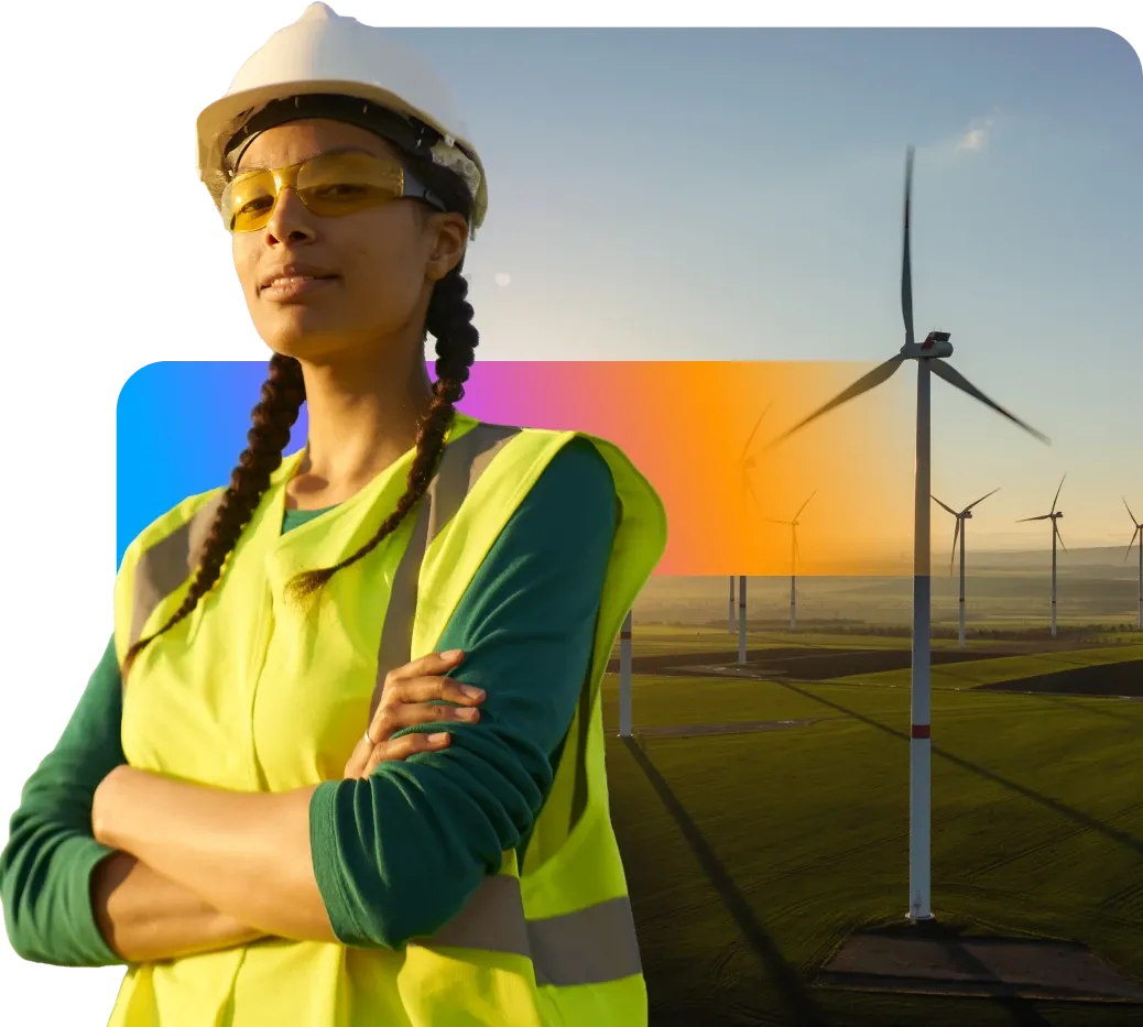 A person in a hard hat and safety vest stands confidently in front of wind turbines at sunset, symbolizing renewable energy and sustainability.