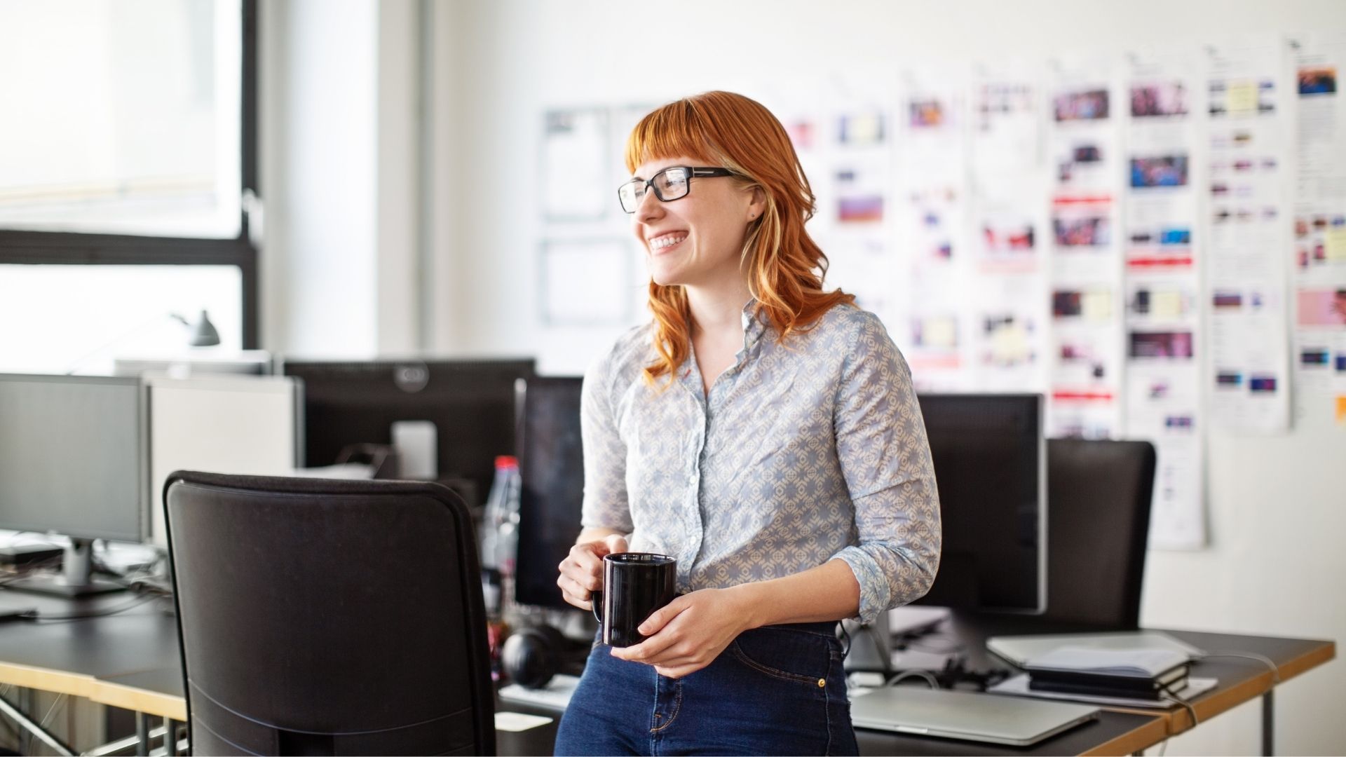 woman in office setting smiling with coffee