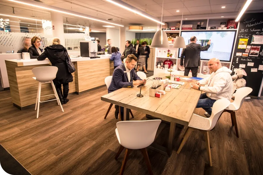 People interacting in a modern bank branch with wooden decor, featuring a reception area, seating, and promotional displays.