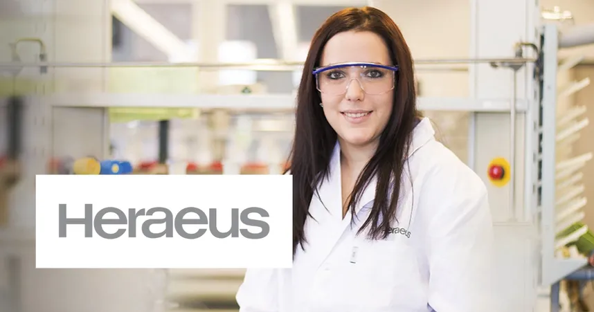 A woman in safety goggles and a lab coat stands in a laboratory. The Heraeus logo is visible in the foreground.