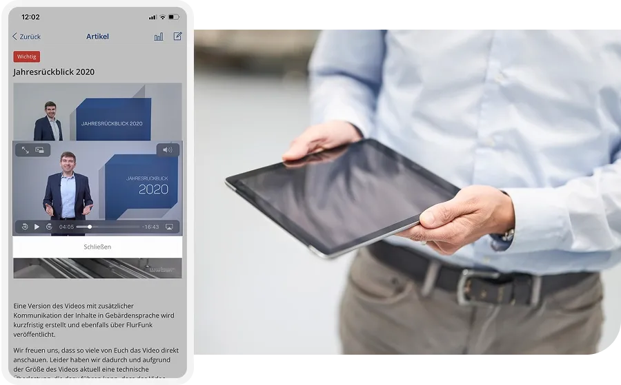 Person in a blue shirt holding a tablet, with a screen showing a video titled "Jahresrückblick 2020" featuring a man in a suit.