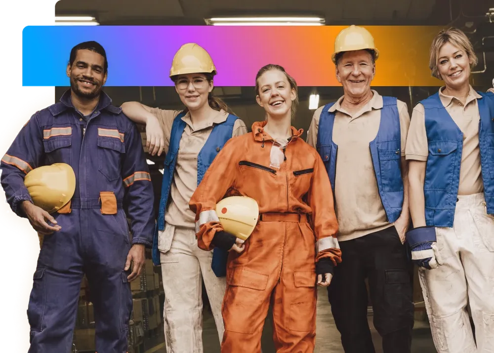 A diverse group of five smiling workers in protective gear and helmets, standing together in an industrial setting.