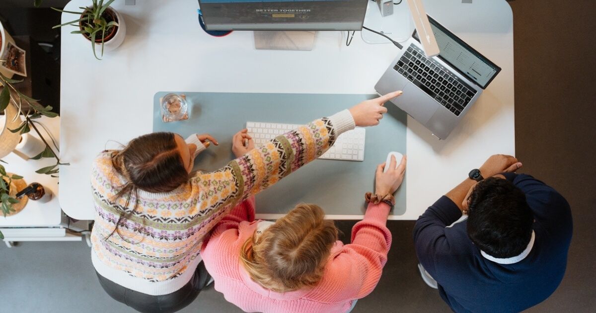 Drei Menschen an einem Schreibtisch bei der Redaktionsplanung