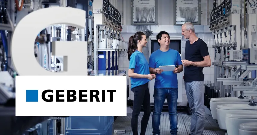 Three people in a modern industrial setting, smiling and discussing. The Geberit logo is visible in the foreground.