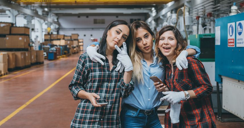Junge Mitarbeiterinnen mit Smartphone in der Werkshalle