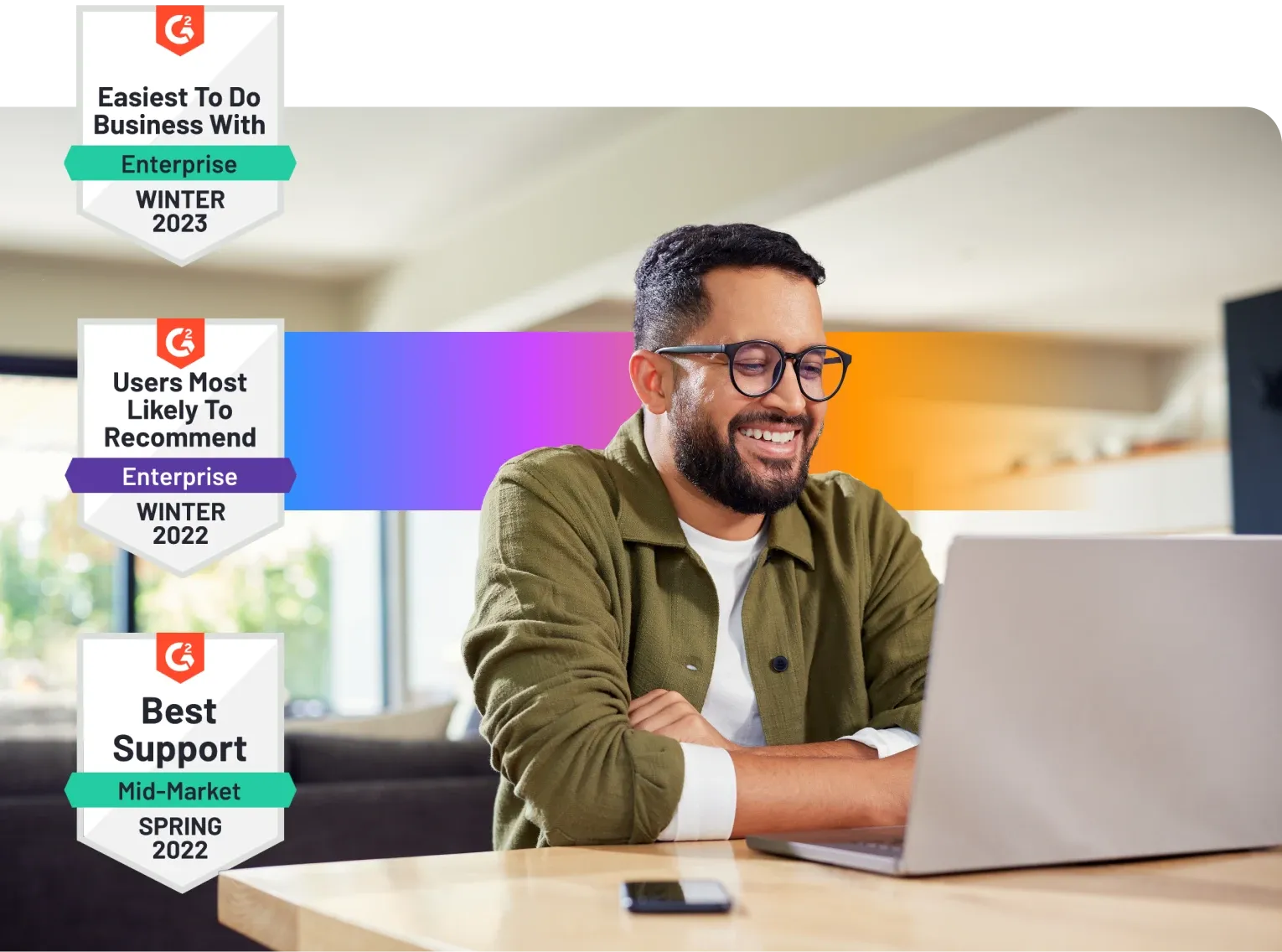 Smiling man using a laptop, with award badges for business ease, user recommendation, and support in the background.