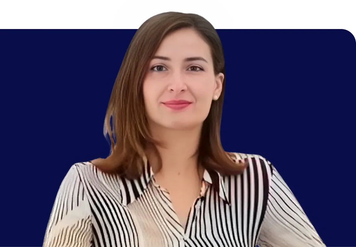 A person with shoulder-length hair wearing a striped shirt, smiling against a dark blue background.