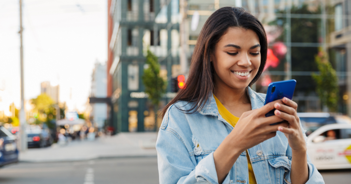 woman smiles into her mobile phone in a city