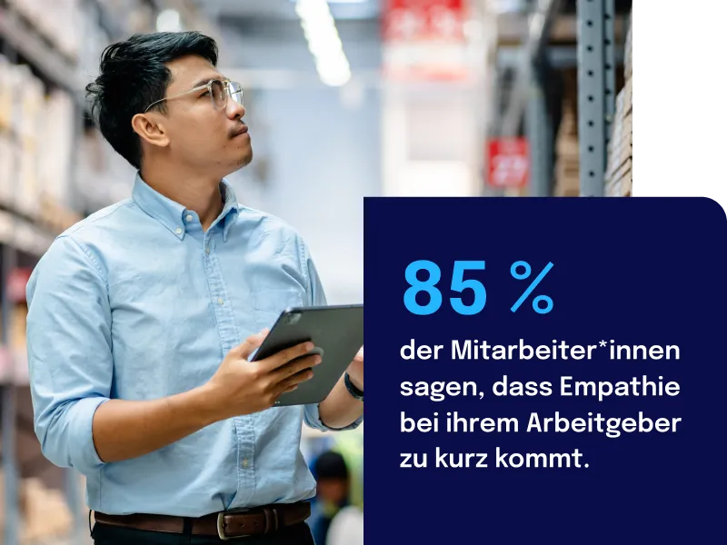 Man in a warehouse holding a tablet, with text stating 85% of employees feel empathy is undervalued by their employer.