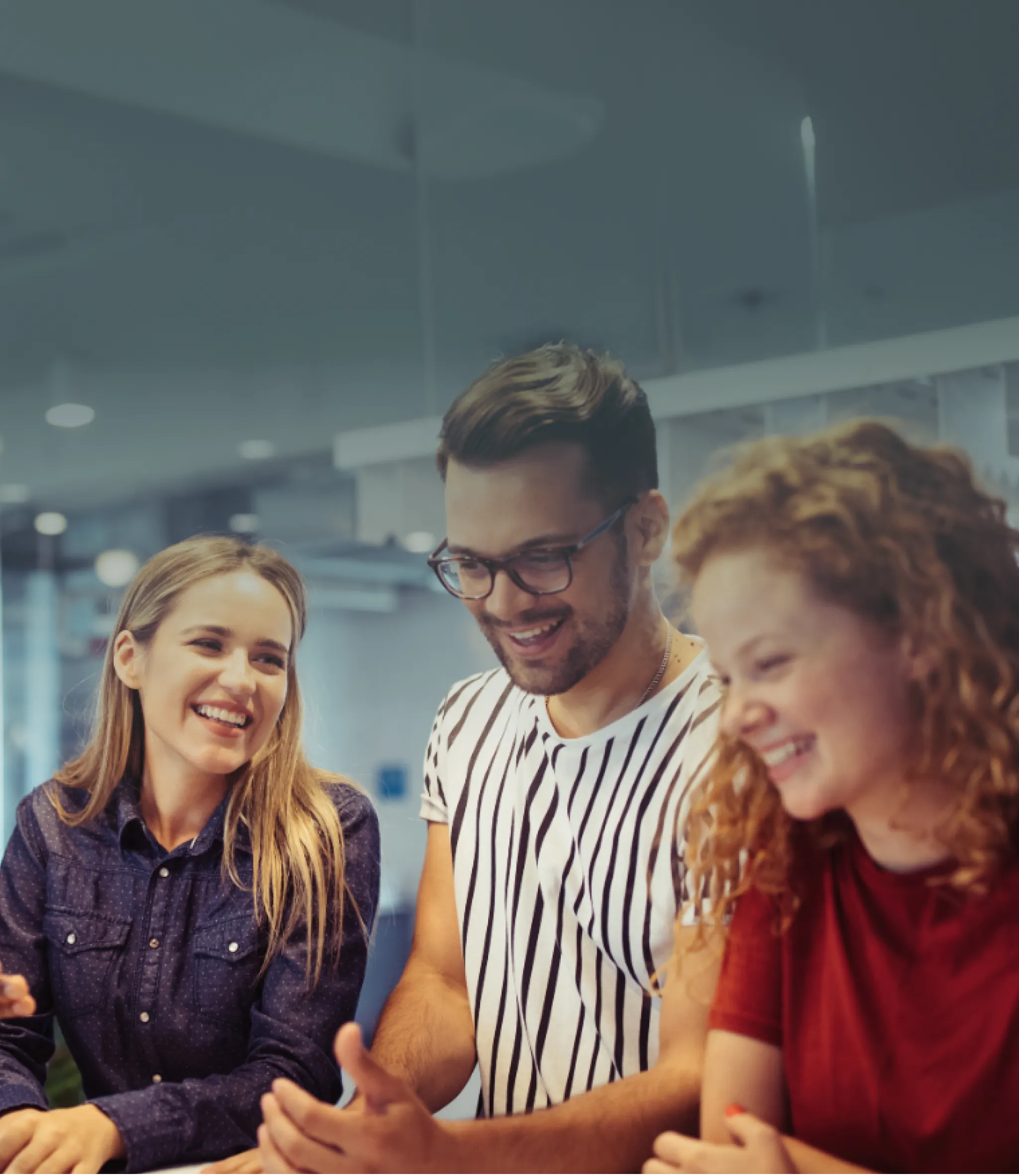 rei Mitarbeitende arbeiten entspannt mit Laptops in einem modernen Bürobereich mit großen, türkisfarbenen Sitzsäcken.
