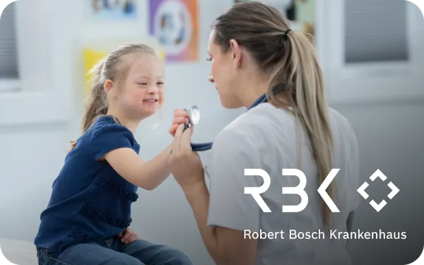 A doctor shows a stethoscope to a smiling child with Down syndrome at Robert Bosch Krankenhaus.