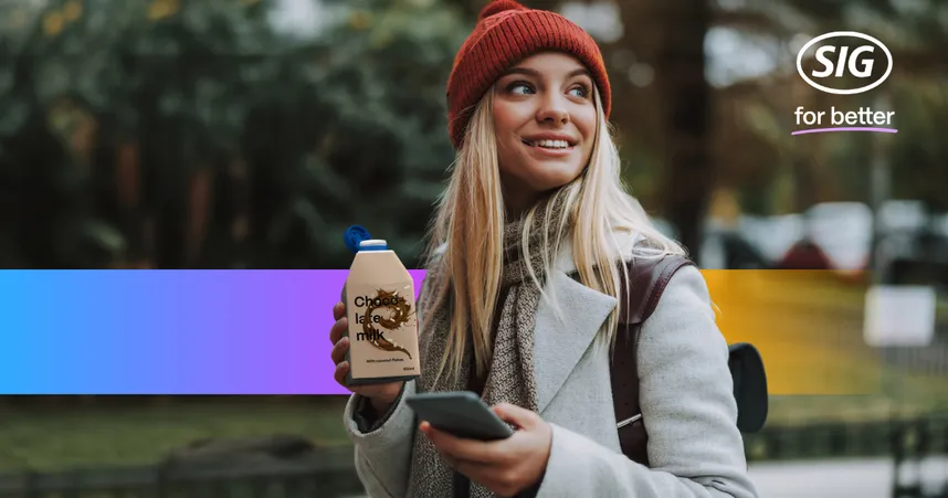 Woman in a red beanie and gray coat holding a drink carton and phone, walking outdoors. SIG logo in the top right corner.