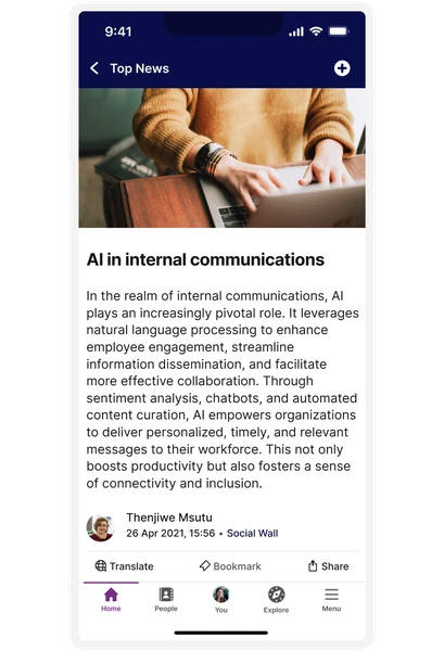 A person using a laptop, with an article on AI in internal communications displayed on a smartphone screen.