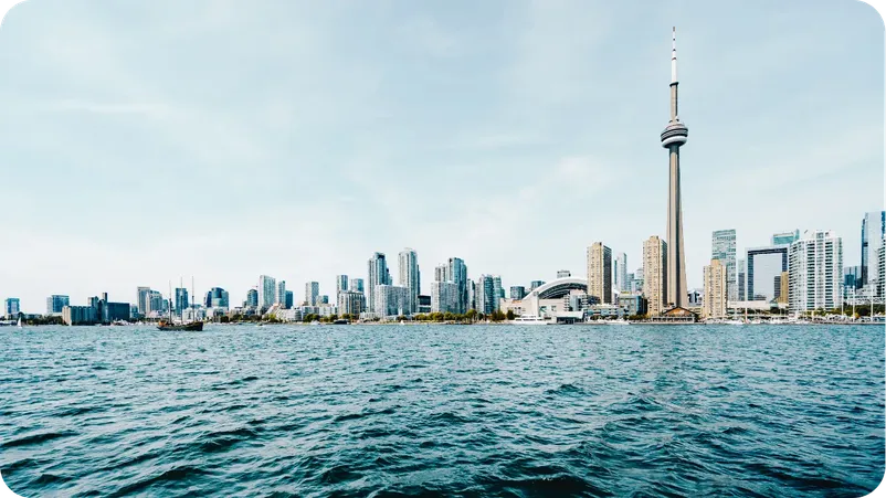 Toronto waterfront skyline with the CN Tower and harbor boats under a clear sky.