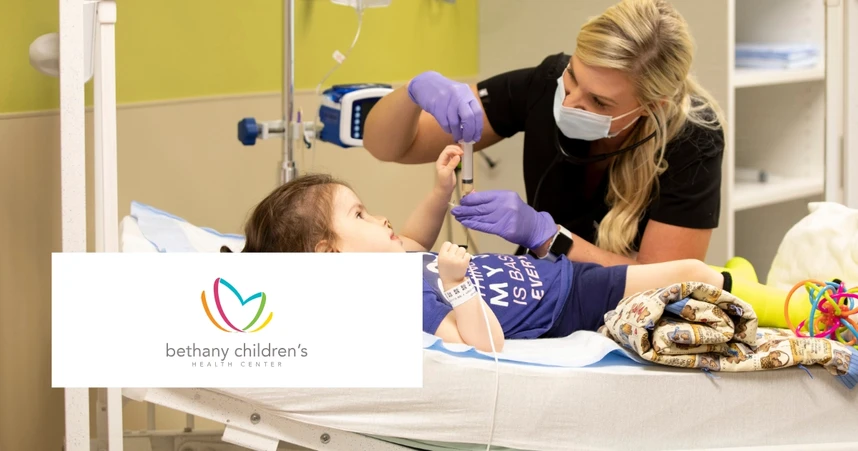 A healthcare worker in a mask and gloves tends to a child on a hospital bed. The logo reads "Bethany Children's Health Center."