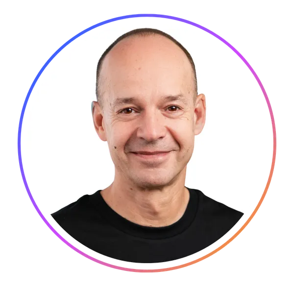 Smiling person with a shaved head wearing a black shirt, framed in a circular border with a gradient color.