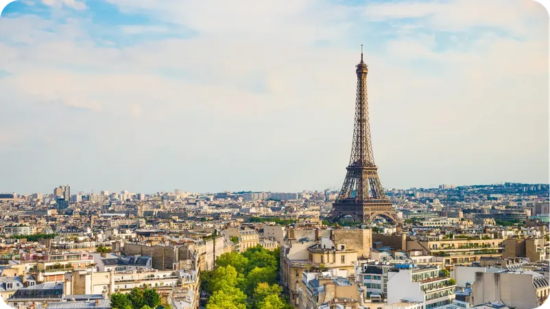 The Eiffel Tower rising above the Paris rooftops under a partly cloudy sky. Title: Eiffel Tower Skyline View, Paris