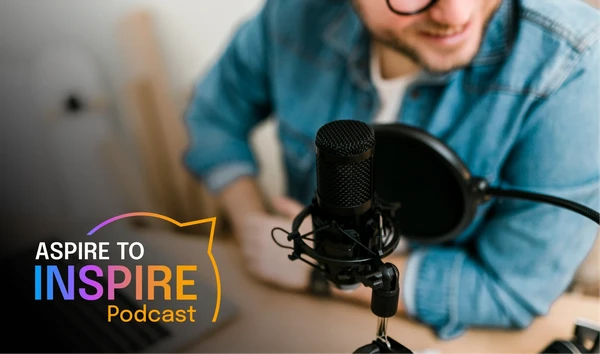 Person in denim shirt speaking into a microphone, with "Aspire to Inspire Podcast" logo visible in the foreground.