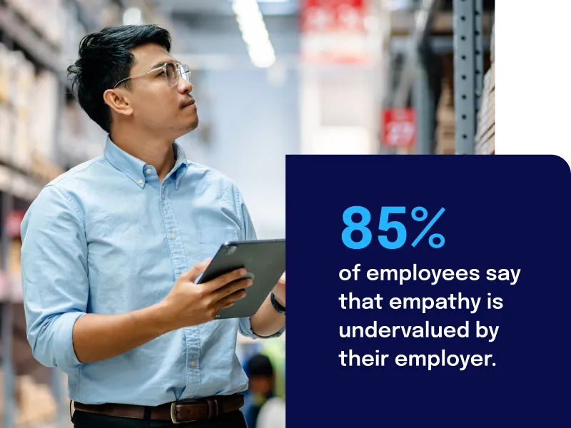 Man in a warehouse holding a tablet, with text stating 85% of employees feel empathy is undervalued by their employer.