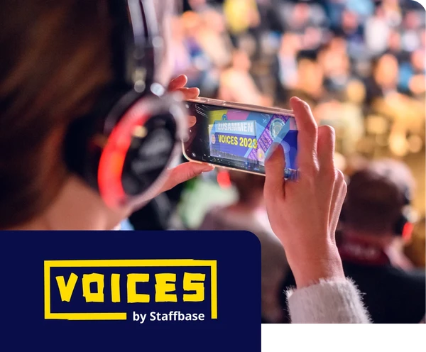 Person wearing headphones records a blurred event on their phone. "VOICES 2023" is visible on the screen. Event logo in the corner.