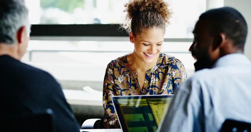 coworkers smiling with open computers and bright lighting