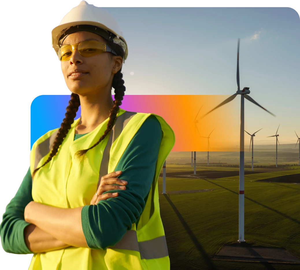 A person in a hard hat and safety vest stands confidently in front of wind turbines at sunset, symbolizing renewable energy and sustainability.