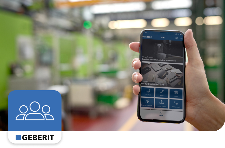 Hand holding a smartphone displaying the Geberit app in a modern industrial setting, with green machinery in the background.