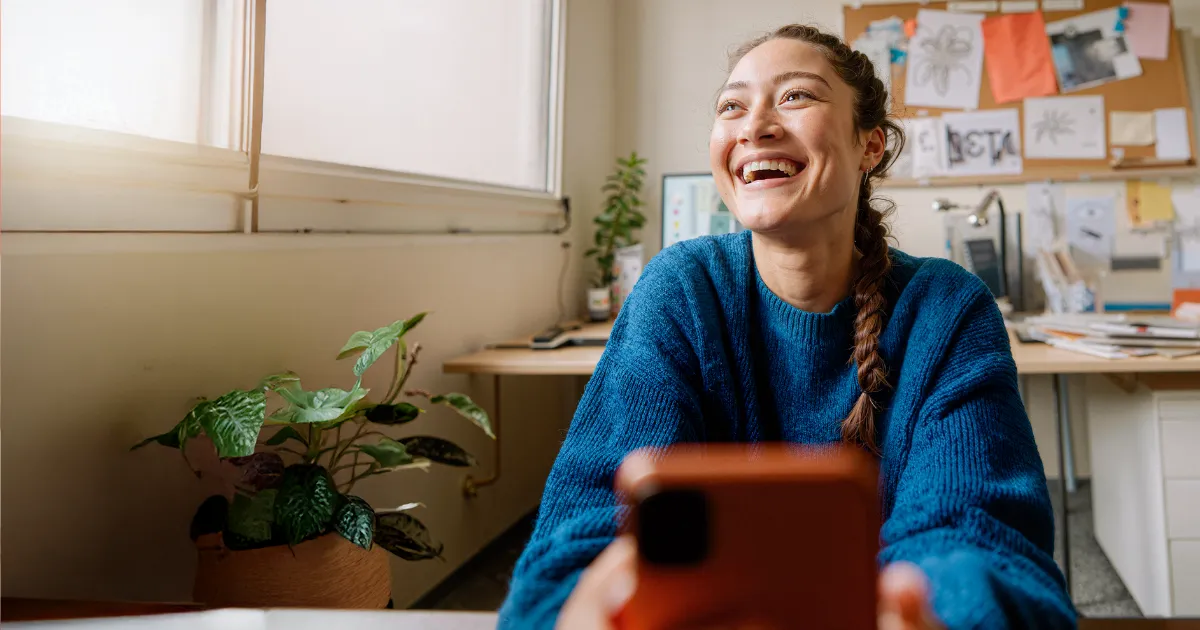 woman laughing in office while holding phone