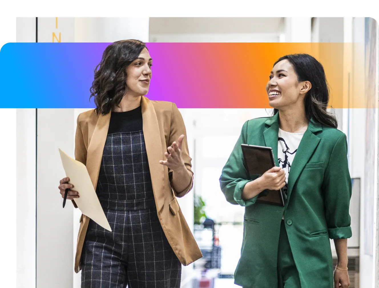 Two women in business attire walking and talking in a hallway, holding documents, with a colorful gradient overlay above them.