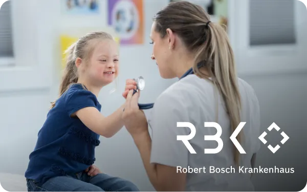 A doctor at Robert Bosch Krankenhaus smiles at a young girl during a check-up, holding a stethoscope.
