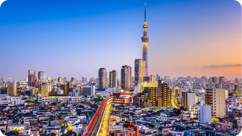 Tokyo Skytree tower rising above the city skyline at dusk, with illuminated streets below.