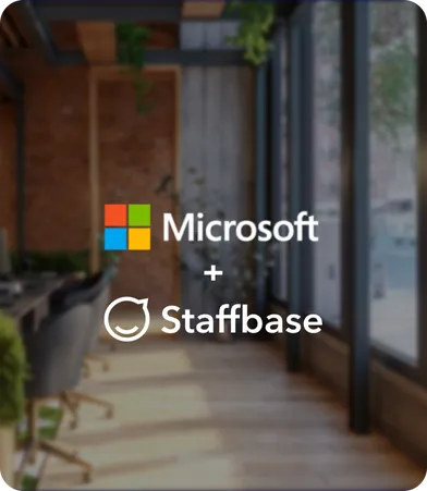 Logos of Microsoft and Staffbase over an office interior with large windows and wooden flooring.