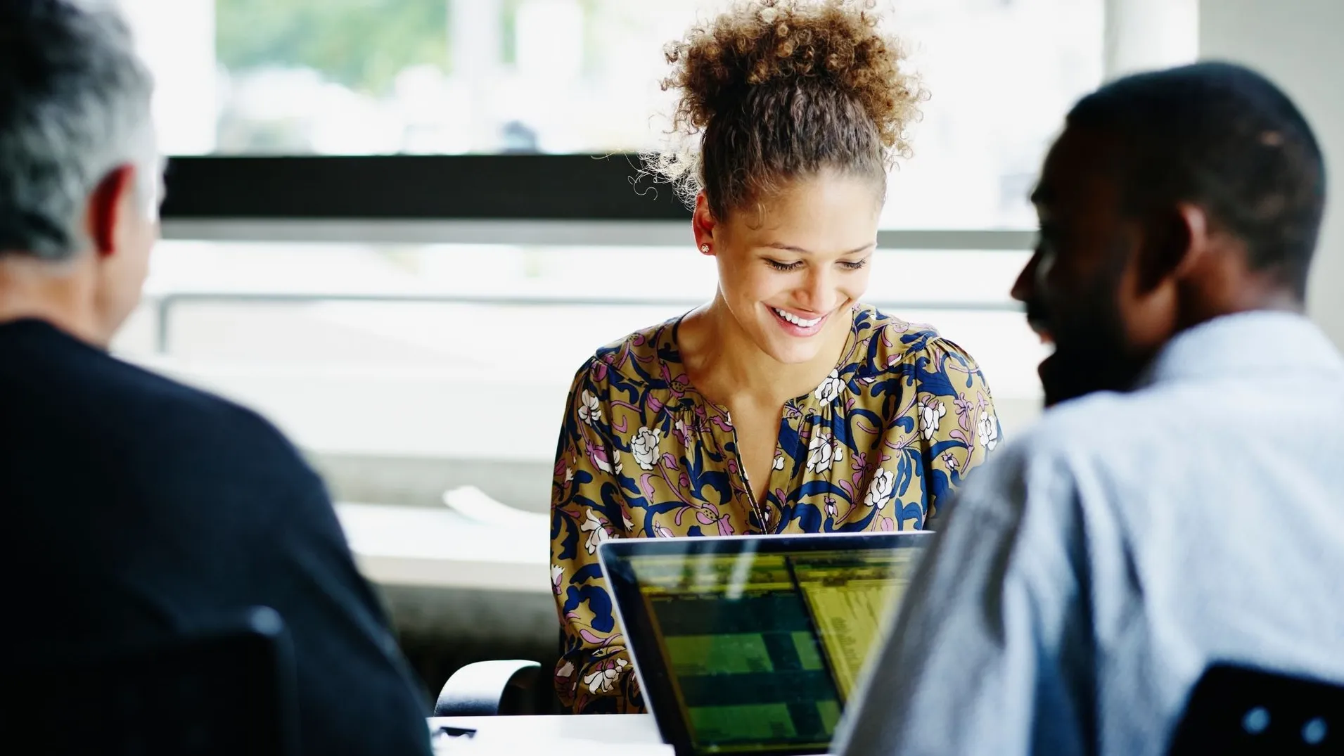 coworkers smiling with open computers and bright lighting