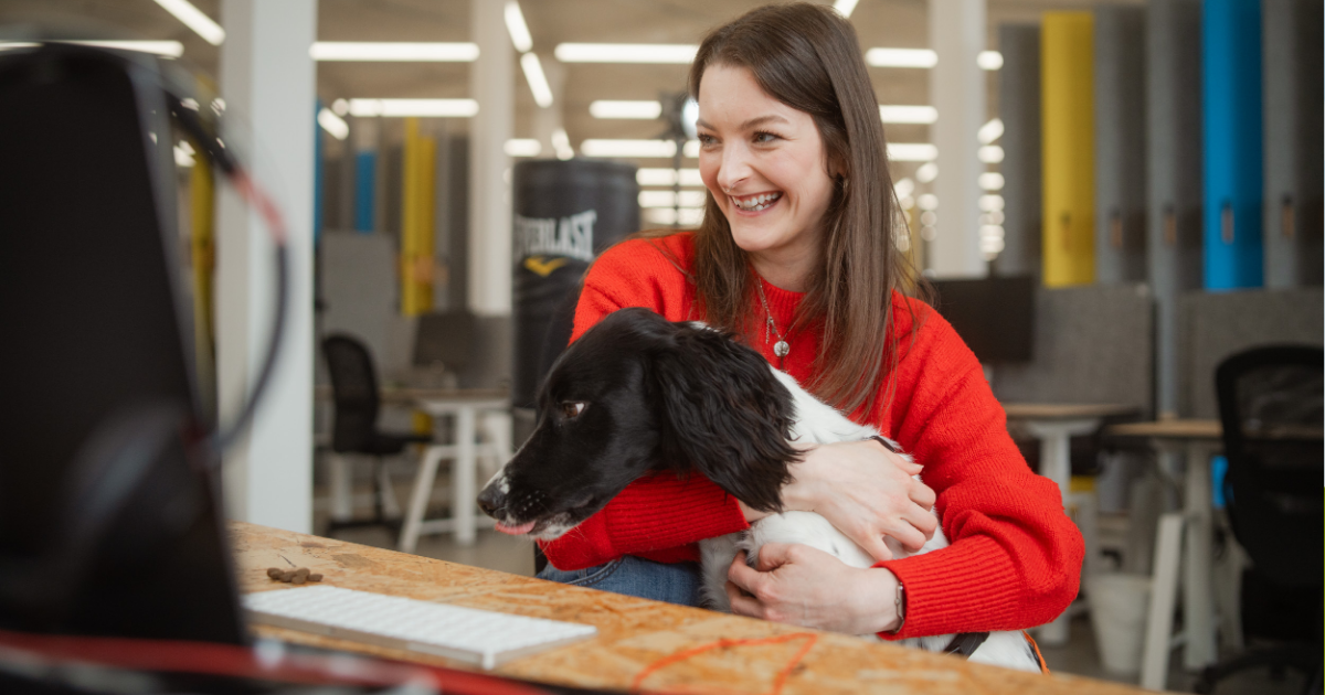woman in office with dog smiling at computer