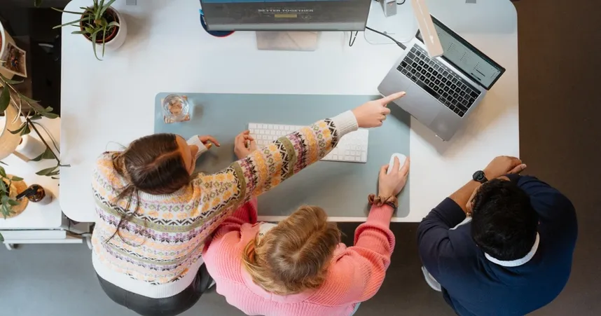 Drei Menschen an einem Schreibtisch bei der Redaktionsplanung