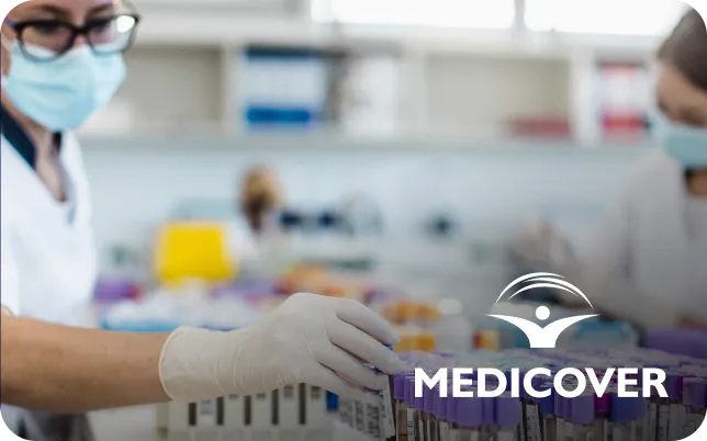 Two lab technicians wearing masks and gloves handle samples in a laboratory. Medicover logo is visible.