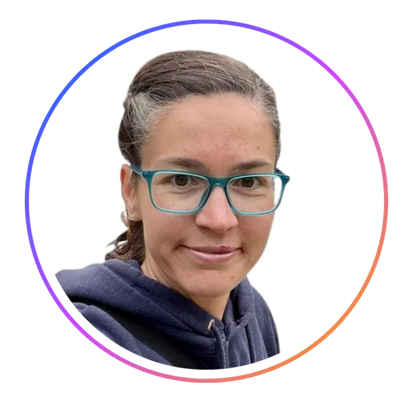 Person with glasses and dark hair tied back, wearing a navy hoodie, inside a circular frame with a gradient border, on a white background.