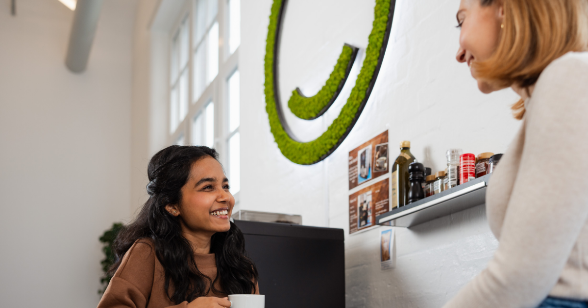 two women smiling at work with coffee