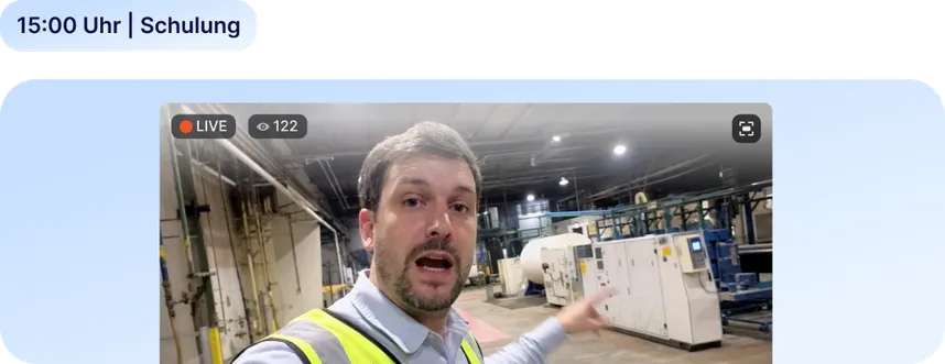 Mitarbeiter in Warnweste moderiert einen Live-Videostream in einer Produktionshalle, 122 Zuschauer